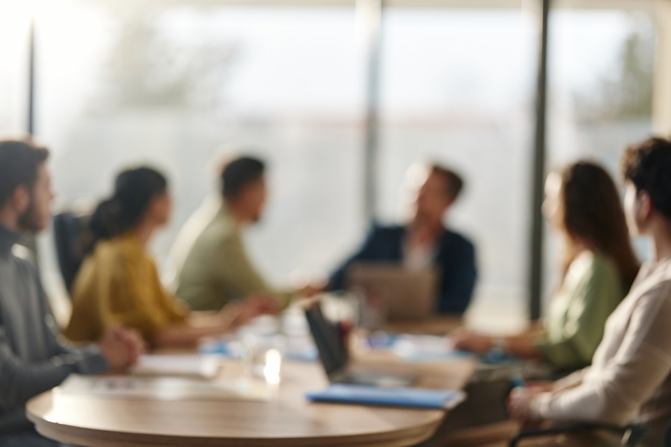 A softly focused group meeting around an office table.